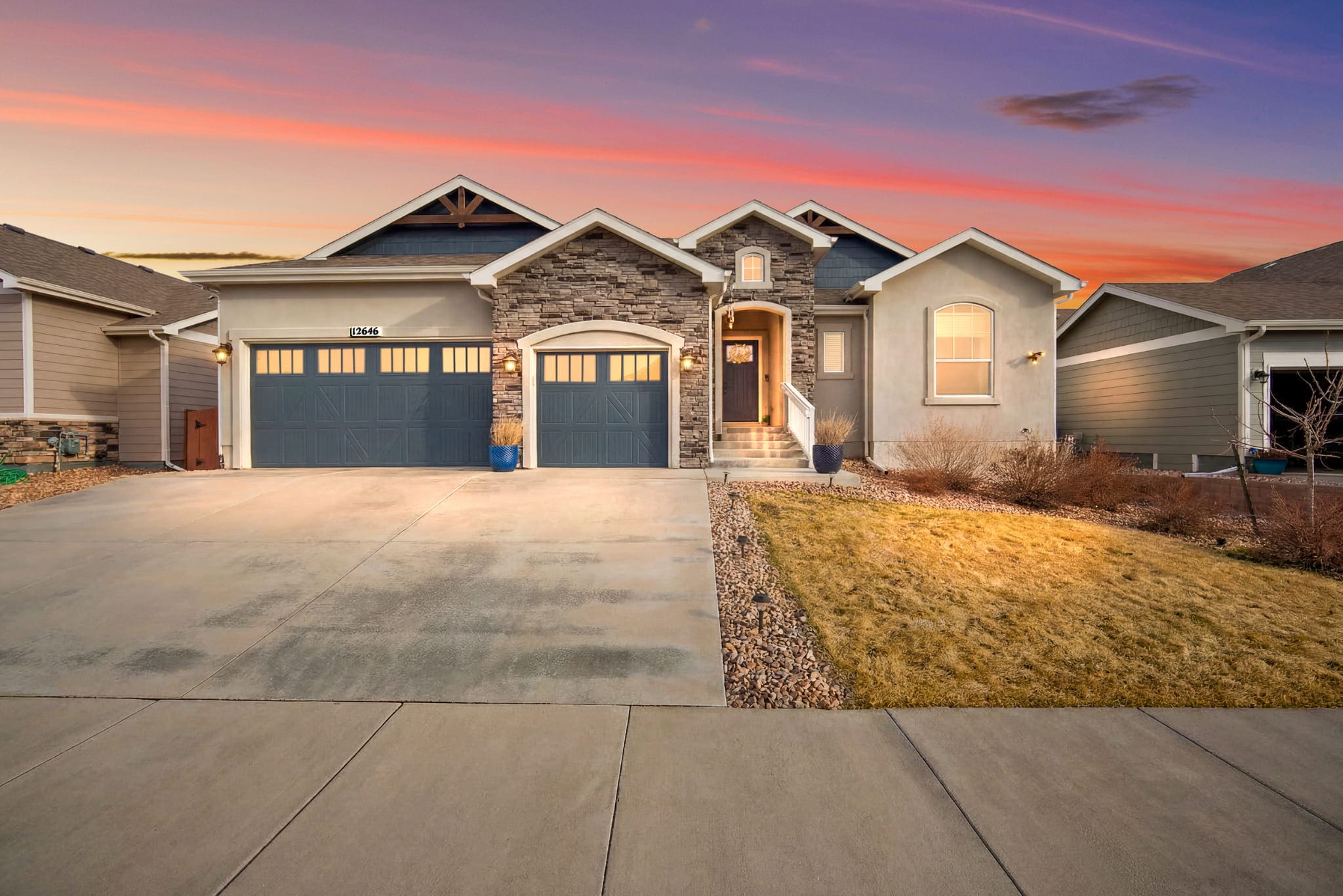 Stone and stucco ranch home with two garage doors at dusk in a Colorado Springs neighborhood