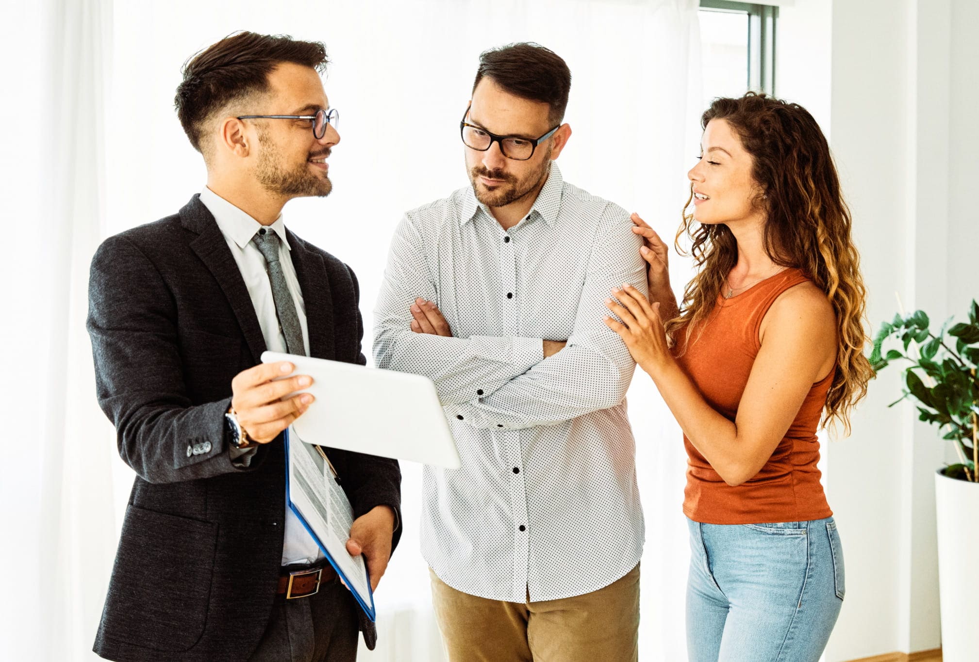 Real estate agent reviewing a home buying plan on a clipboard with a couple